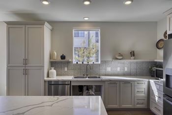 A kitchen with a marble counter top and stainless steel appliances.